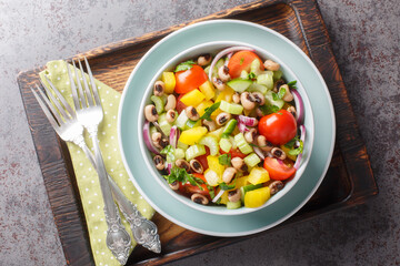 Vegetarian diet salad with vegetables and black-eyed peas close-up in a bowl on a wooden board. horizontal top view from above