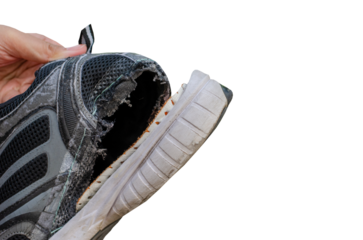 Hand holding an old, torn black shoe behind the heel of the shoe on transparent background