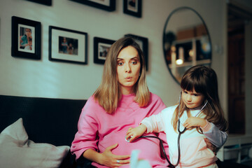 Girl Listening with a Stethoscope on the Pregnant Belly of Her Mom. Bigger sister expecting to meet her little sibling soon  
