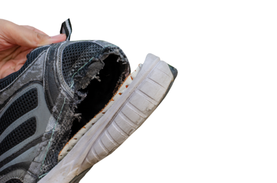 Hand holding an old, torn black shoe behind the heel of the shoe on transparent background
