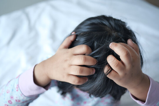  child scratching head sitting on the bed Annoying itch.