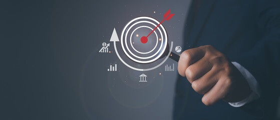 Fototapeta na wymiar Businessman using magnifying glass with arrow dart icon and management target, success and planning. investment goal and target for business investment concept.
