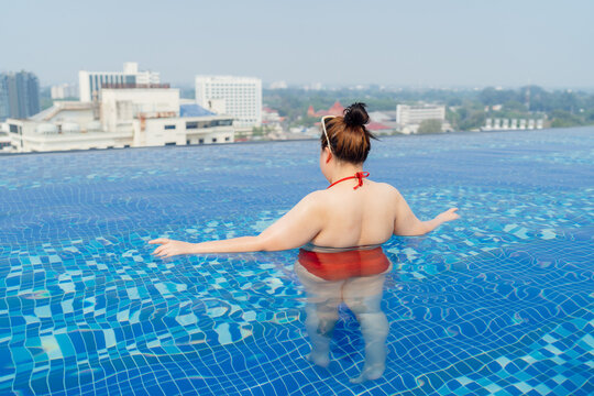 Overweight young asian woman wearing swimsuit relaxing in the pool Happy plus size woman cheery funny Vacation Traveling in summer.