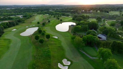 Beautiful manicured golf course in summer during sunset. High aerial establishing shot.