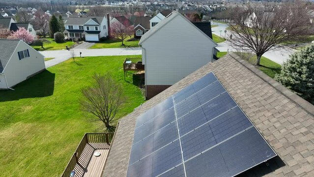 Solar panels on house in USA. Bright day in early spring reflects on solar array for clean and renewable energy in home. Aerial dolly forward.