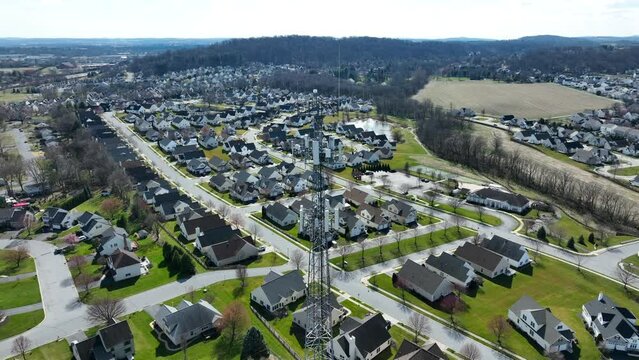 Aerial orbit of tall cell tower providing 5g data to residential neighborhood in USA.