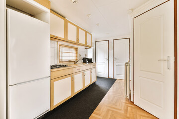 a kitchen with white appliances and wood flooring in the middle of the room, including an open door that leads to another room