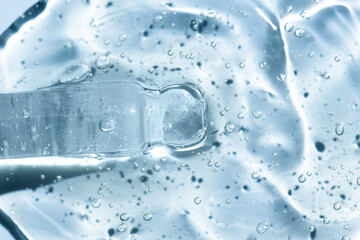 Fototapeta na wymiar Glass dropper with serum on a blue background, top view. Cosmetic liquid gel texture, macro.