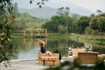 Asian beauty sitting beside pond breathing fresh air drinking tea