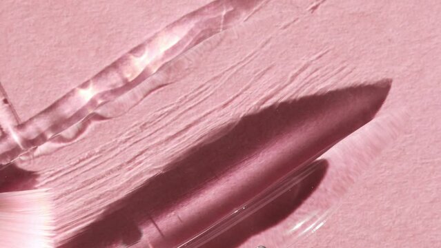 Smear of cosmetic gel, serum on a pink background, top view. A drop of beauty product is smeared with a brush.