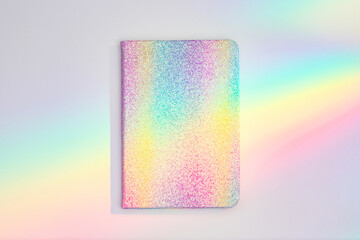 Unicorn colored notepad in rainbow light beam on the desk