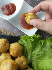 Fried meatballs on a black plate with chili sauce and lettuce