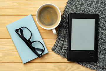 Portable e-book reader on wooden background top view