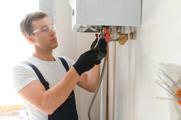 Professional plumber checking a boiler and pipes, boiler service concept - obrazy, fototapety, plakaty
