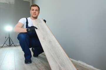 DIY, repair, building and home concept - man lying parquet floor board or laminate flooring