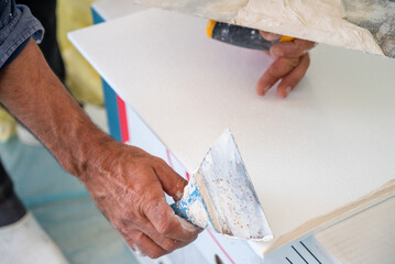 adhesive plaster application of styrofoam ceiling tiles of a home kitchen