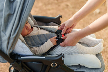 Fototapeta na wymiar woman fastening belt on stroller with crying baby
