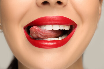 Woman showing her tongue on light background, closeup