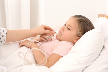 Obraz na płótnie Canvas Mother helping her sick daughter with nebulizer inhalation in bedroom