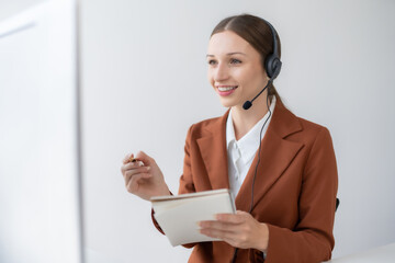 Call center agent woman with headset working on support hotline in modern office. Smiling female...