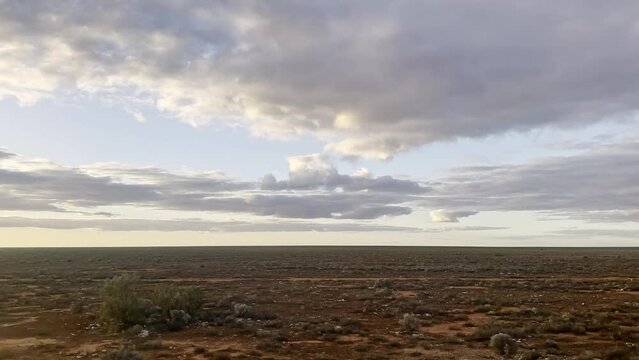 Treeless Nullabor Plain flies past, viewed from speeding Indian Pacific Train in Western Australia. Red dirt and saltbush dominate vast landscape