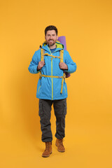 Happy man with backpack on orange background. Active tourism