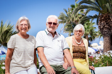 Group of Happy Senior People  Sitting Under the Sun close to the Beach Enjoying Sea Vacation and Freedom. Retirement Lifestyle Concept