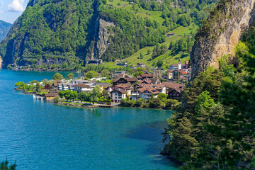 Fototapeta na wymiar Scenic aerial view of Lake Lucerne with Swiss village Sisikon mountain panorama seen from lakeshore on a sunny spring day. Photo taken May 22nd, 2023, Lake Uri, Switzerland.