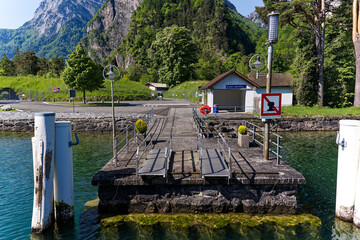Shelter at pier of Swiss village Isleten with white poles and gangways on a sunny spring day. Photo...