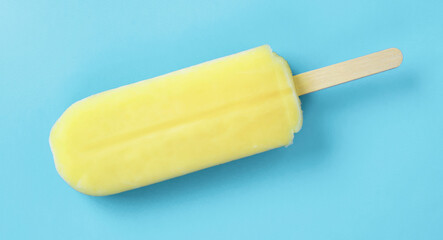 Close up of a yellow popsicle on the light blue background. 水色背景上の黄色のアイスキャンディのクローズアップ