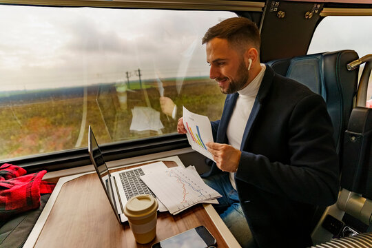 Businessman commuting by train, talking for a video call via laptop,discusses project results and data research