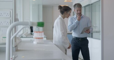 Doctor and Sales Representative Meeting in Laboratory and looking at Digital tablet