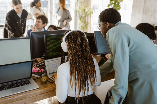Multiracial programmers discussing over laptop at desk in office