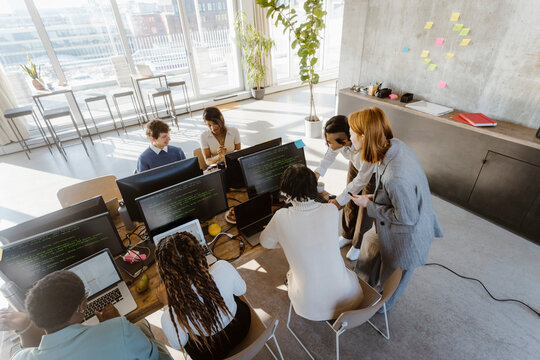 High angle view of programmers working on computers at desk in creative office