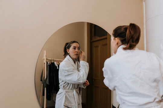 Non-binary Person Using Eyebrow Pencil While Looking In Mirror At Home