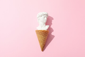 Waffle cone with ancient head on pink background