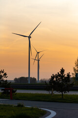 Wind turbines against the background of an orange setting sun. Renewable energy sources in the fight against high energy costs