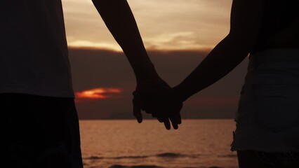 Love couple holding hands on sea sunset background. Close up silhouette man and woman touching hands together at sunset beach. Romantic couple couple holding each other hand's enjoying romantic date