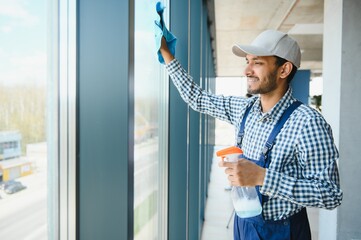 Male janitor cleaning window in office