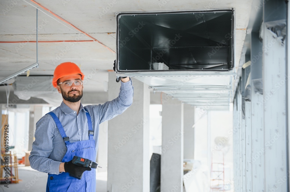 Wall mural Industrial Theme. Warehouse Heating and Cooling System Installation by Professional Caucasian Technician. Commercial Building Ventilation Rectangle Canals. Air Distribution.