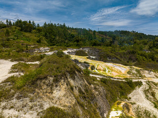 Fototapeta premium Aerial drone of geothermal landscape with hot boiling sulphur river and springs due to volcanic activity. Sipoholon Hot Spring. Sumatra, Indonesia.