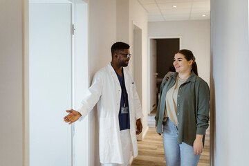 Male nurse assisting female patient while entering in consulting room at hospital