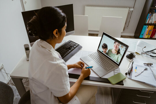 High angle view of female pediatrician consulting mother and son over video call on laptop at clinic