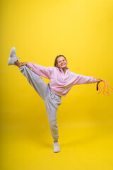 Fototapeta na wymiar Beautiful sportsgirl with skipping rope isolated on yellow studio