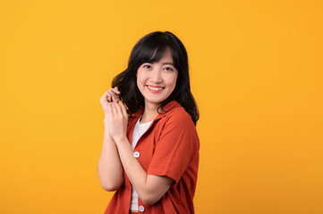 Portrait beautiful young asian woman cute and shy dressed in orange clothes isolated on yellow studio background.