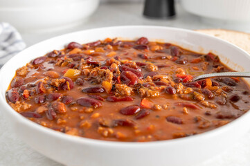 Kidney bean stew with ground beef, tomatoes, bell peppers, onions, garlic and herbs on a plate with spoon