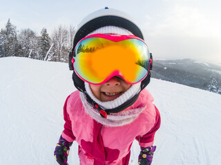 Fototapeta na wymiar Little Cute Girl Snowboarding at ski resort in sunny winter day