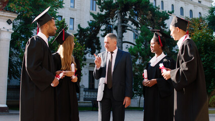 Happy college professor congratulated his students on their graduation day in the college garden...