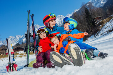 Mother with small kids sit in the snow wear sport outfit