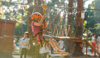 happy little girl in a rope park on the wood background
